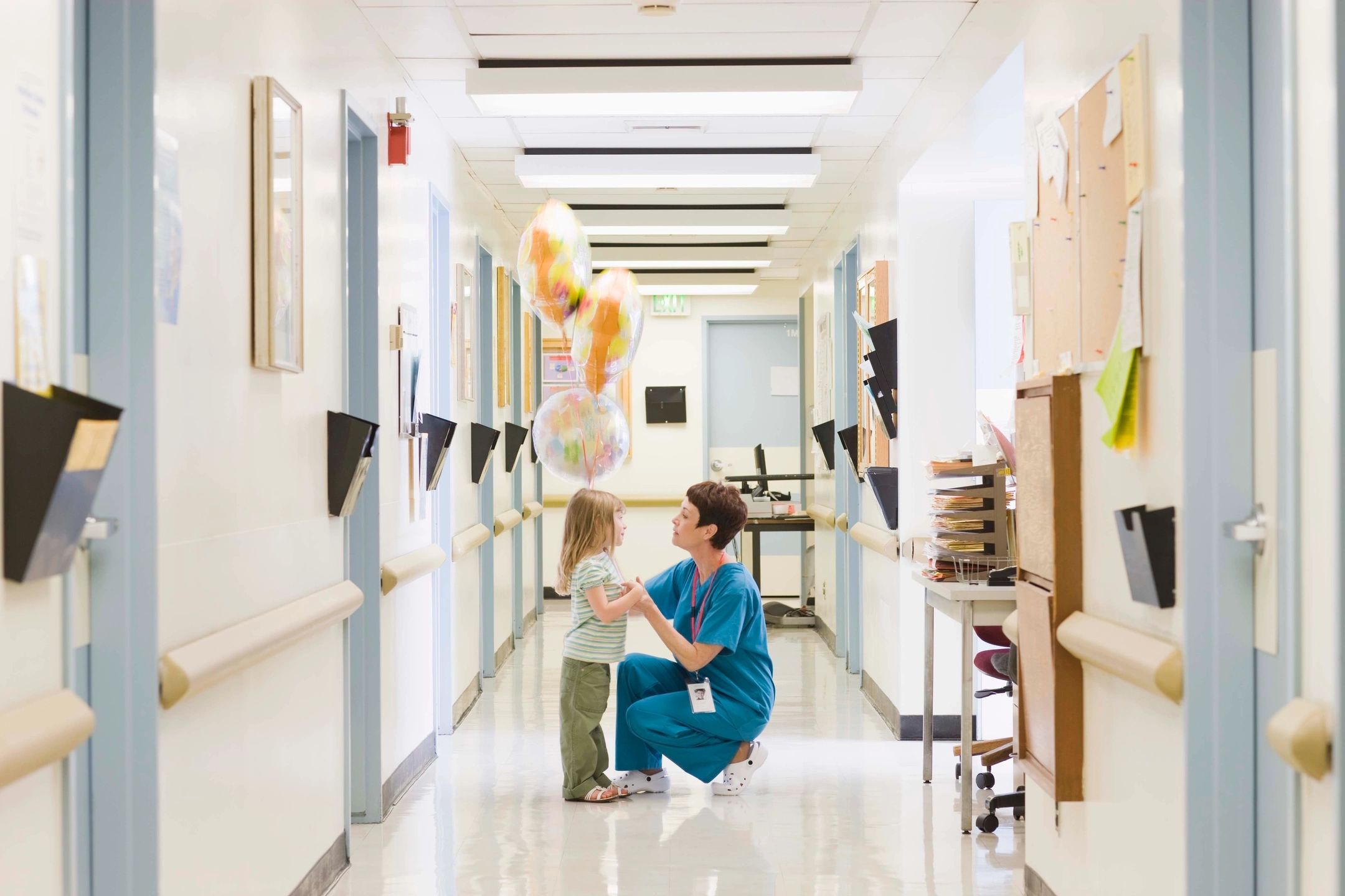 A woman kneeling down in the hallway with a child.