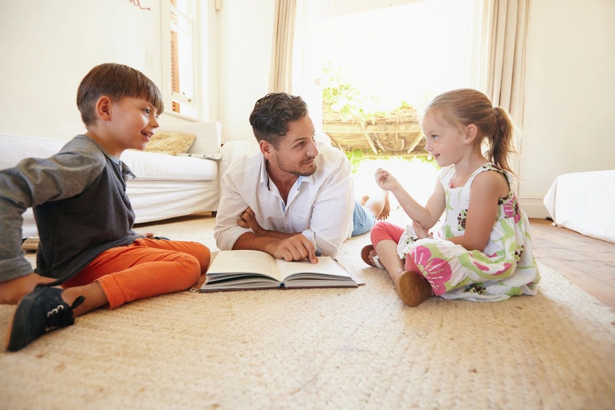 A man and two children are sitting on the floor