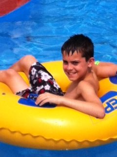 A boy in the pool on an inflatable raft.