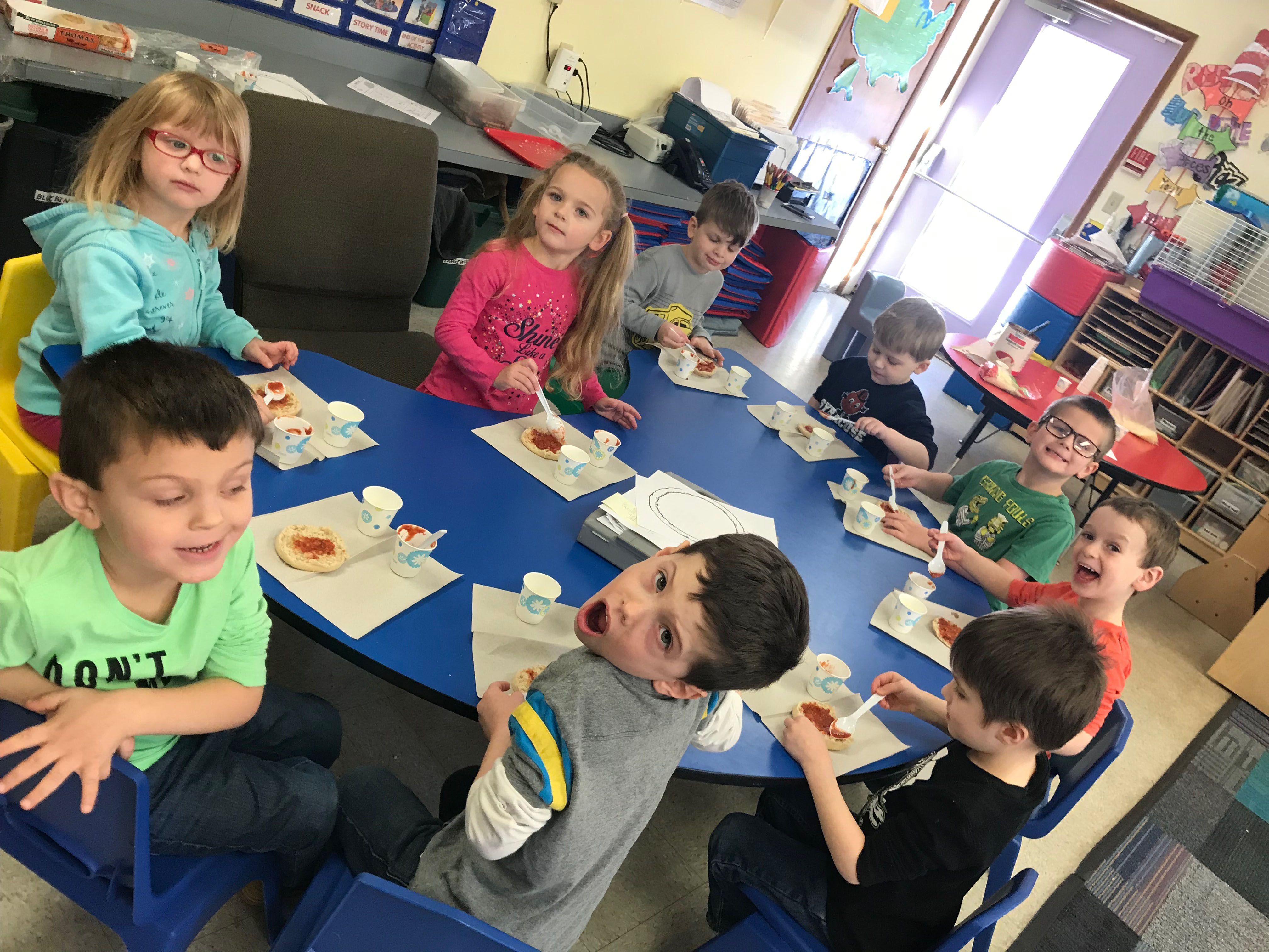 A group of children sitting at the table eating food.