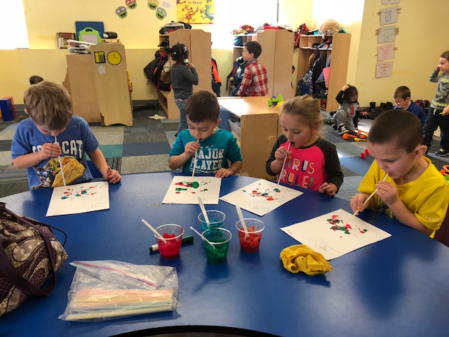 A group of children sitting at a table with paper.