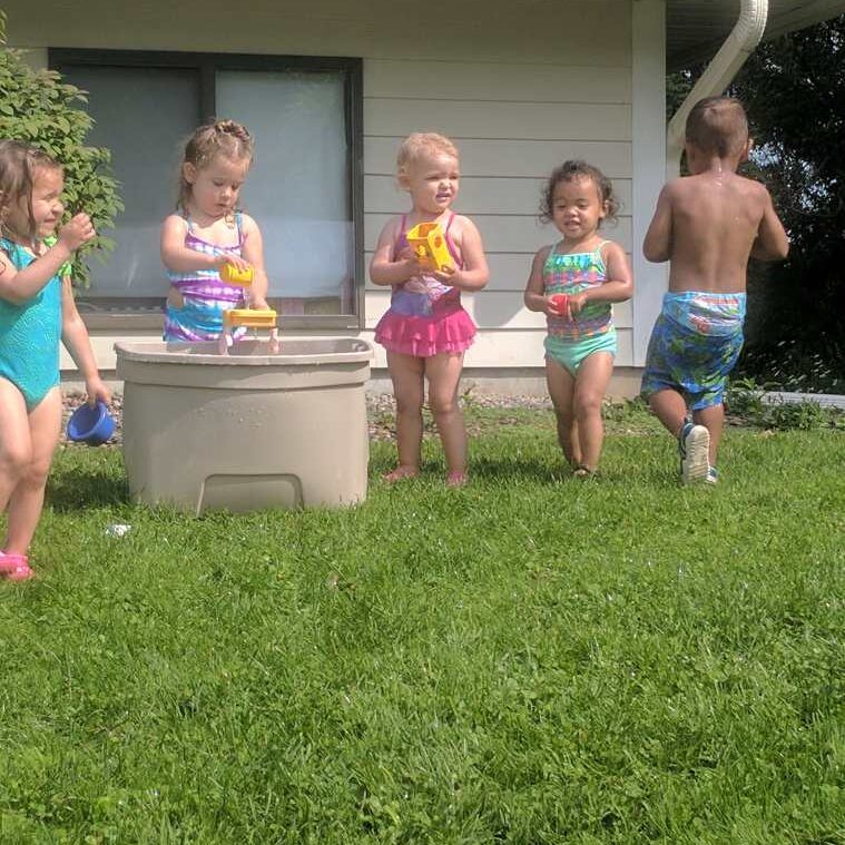 A group of children playing with water in the yard.